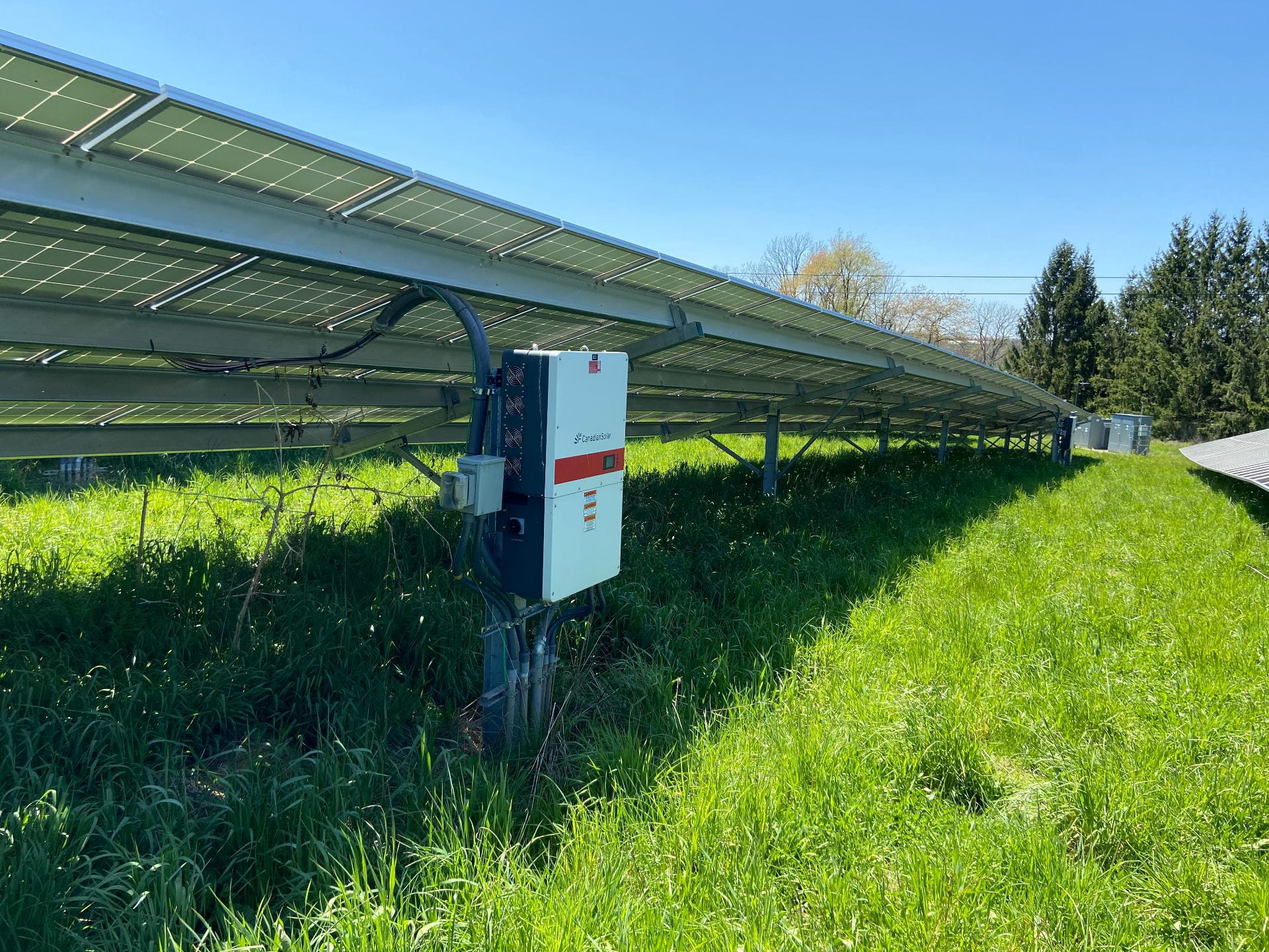 The under-side of a long row of solar panels, showing an inverter. Credit: Penn State MCOR