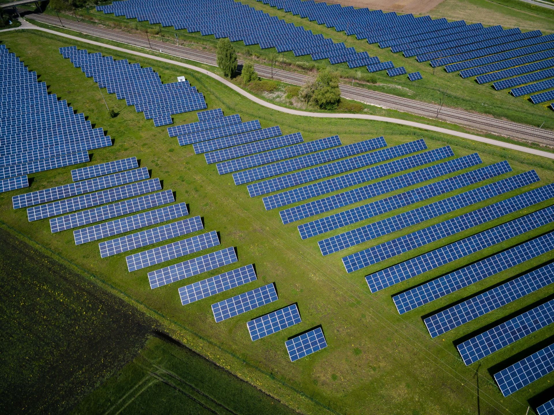 Aerial view of solar panels, road, and crop fields. Credit: Andreas Gucklhorn, Unsplash, https://unsplash.com/photos/Ilpf2eUPpUE