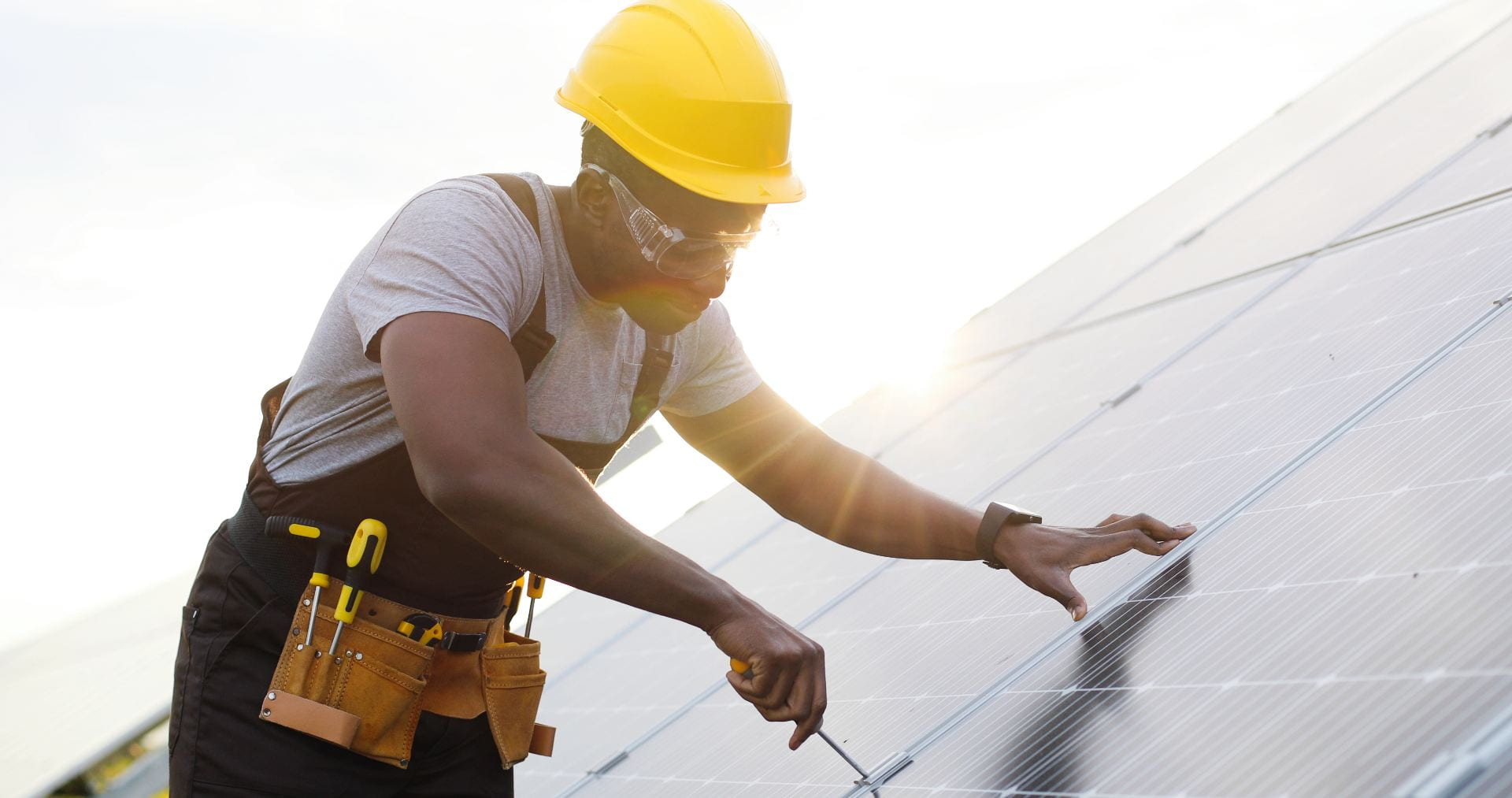 Man using a screwdriver to affix a solar panel. Credit: VAKS-Stock Agency/https://shutterstock.com