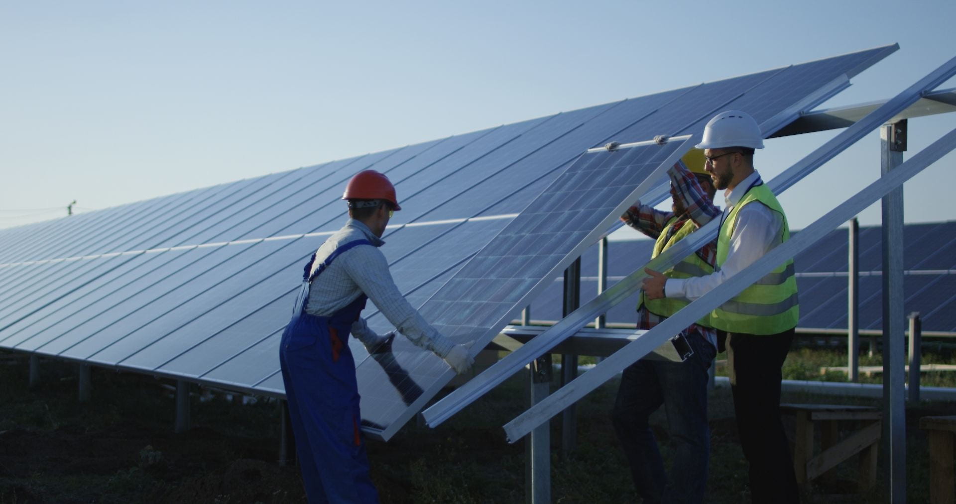 Three men installing a solar panel in a large solar array. Credit: Frame Stock Footage/Shutterstock.com